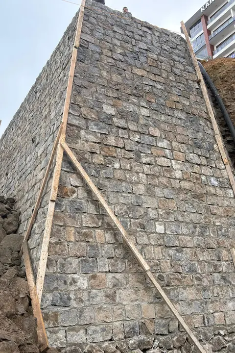 Taş örülmüş, kenarları ahşapla desteklenmiş istinat duvarı